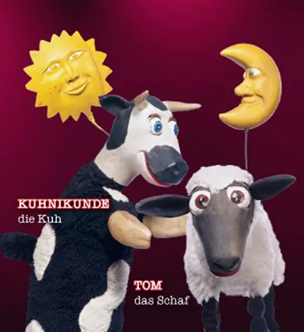 Die Kuh Kuhnikunde und das Schaf Tom, dahinter eine lachende Sonne und ein Mond